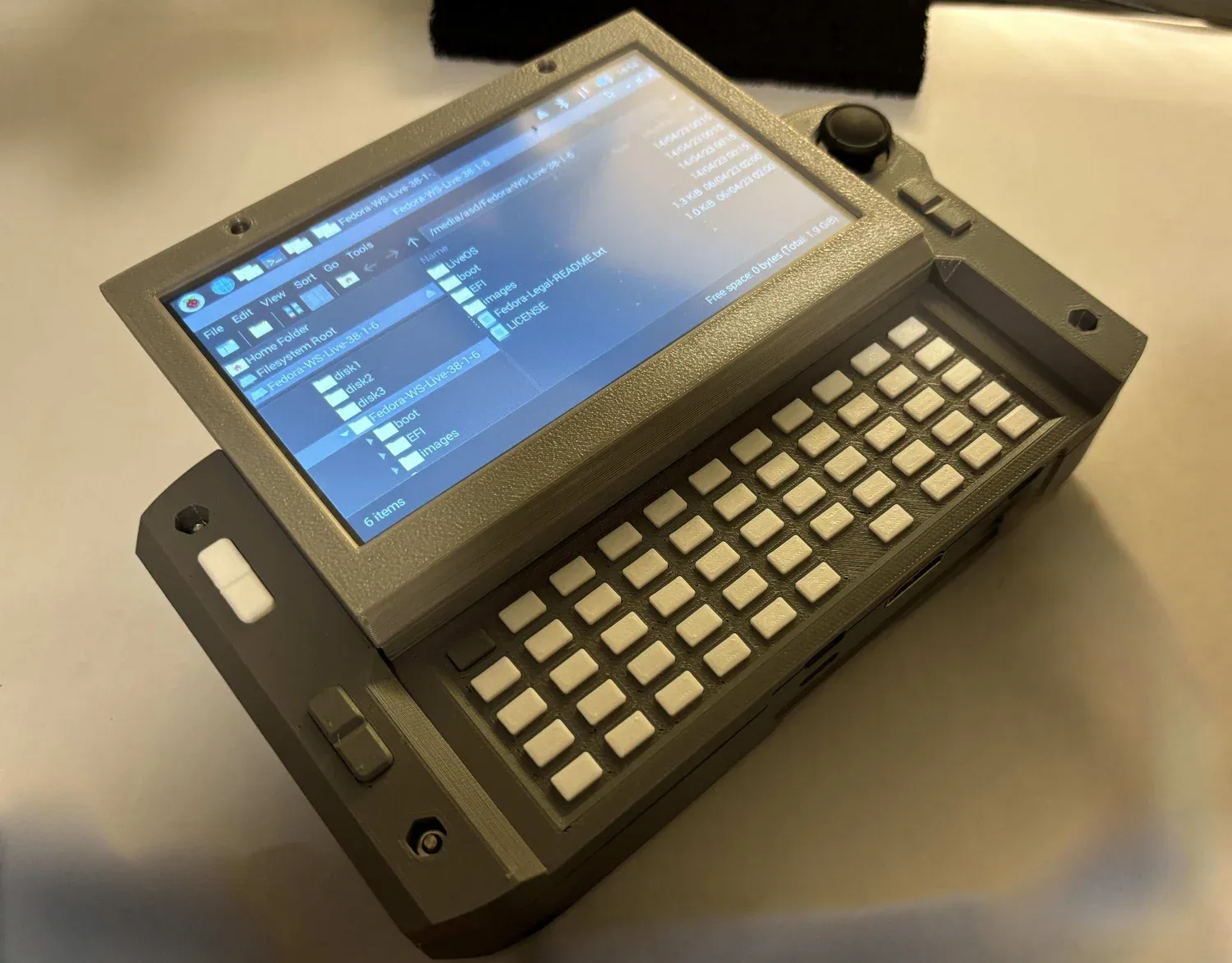 A handmade gray cyberdeck computer with a built-in screen and compact keyboard