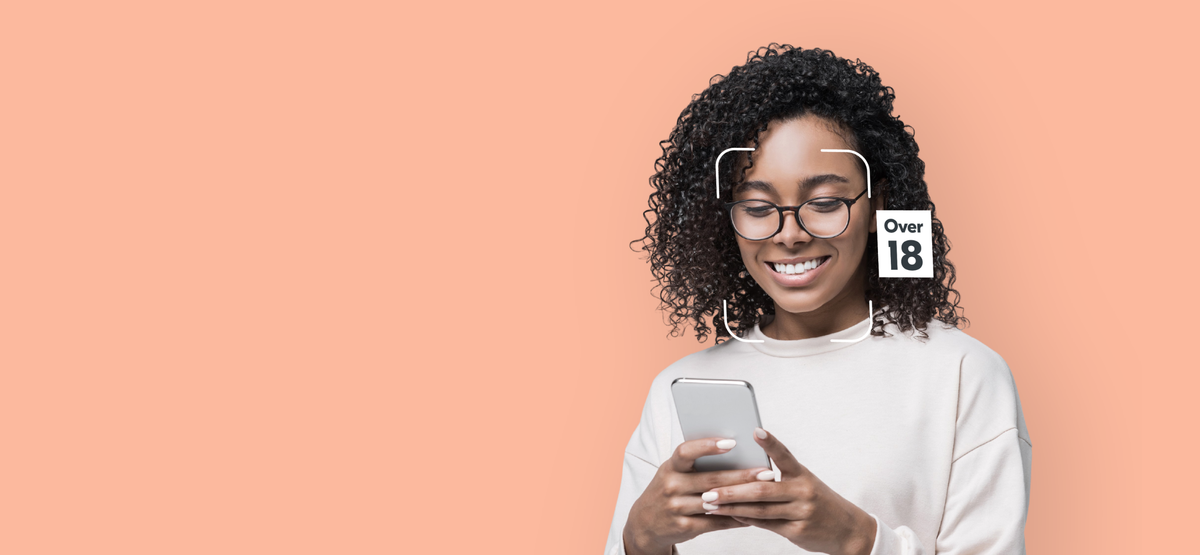 A woman using a phone while facial age estimation marks her as over 18